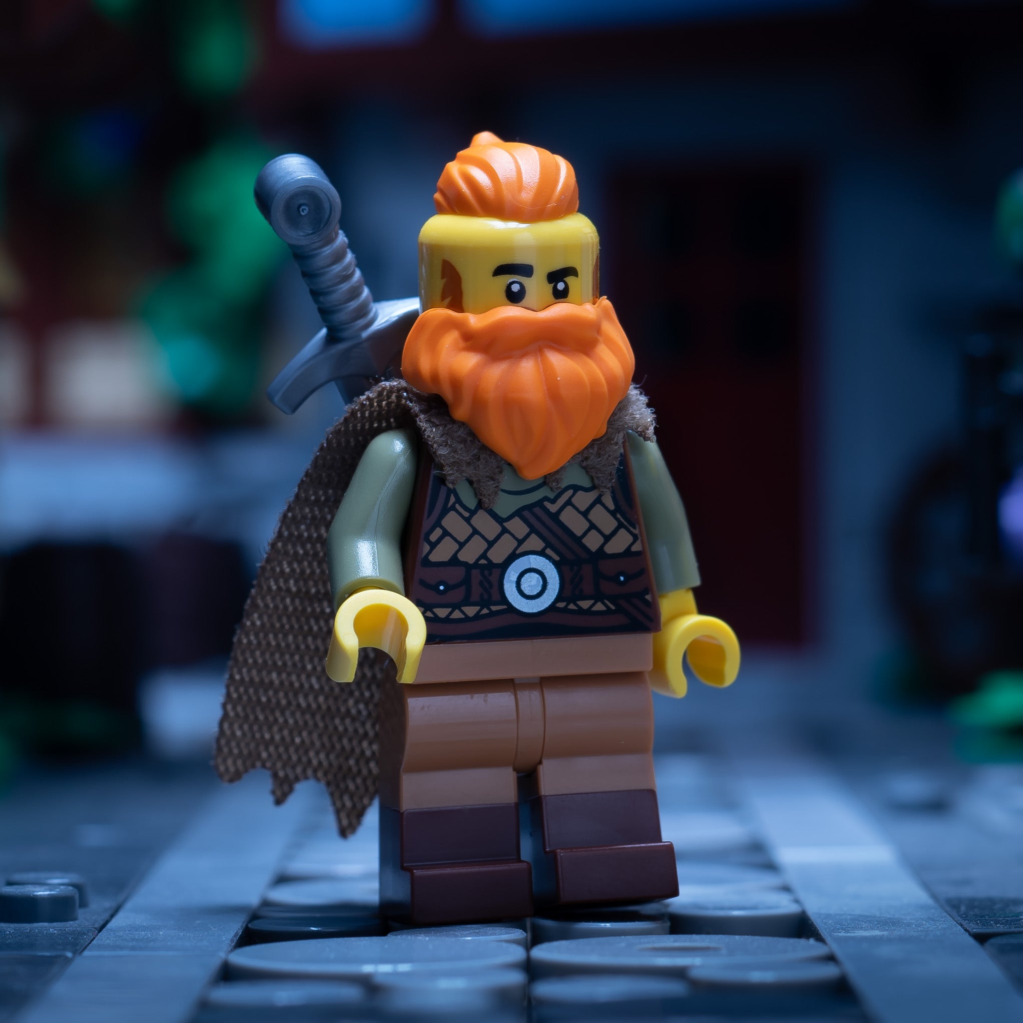 A LEGO minifigure of a bearded warrior wearing a cape with a sword on his back